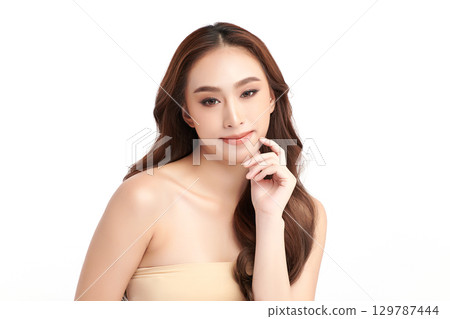 A beautiful young Asian woman with clean, fresh skin against a white background. Skincare, facial treatment, cosmetology, beauty, and spa. An elegant portrait of an Asian woman. 129787444