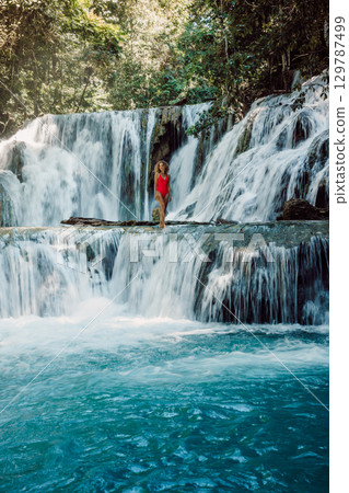 Woman on scenic cascade waterfalls with clear water in Indonesia 129787499