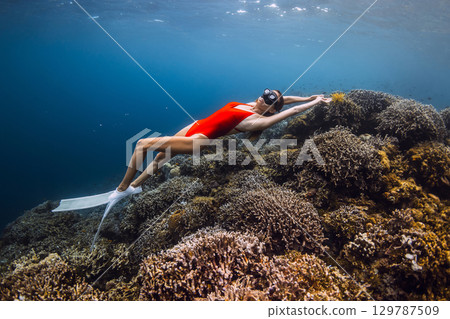Freediver glides in underwater with living corals. Free diving in Raja Ampat Freediver glides in underwater with living corals. Free diving in Raja Ampat 129787509