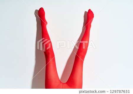 Long female legs oin red tights over white wall background. Long female legs oin red tights over white wall background. 129787631