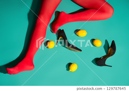 Womans legs in bright red tights and high heels with scattered lemons and purse Womans legs in bright red tights and high heels with scattered lemons and purse 129787645