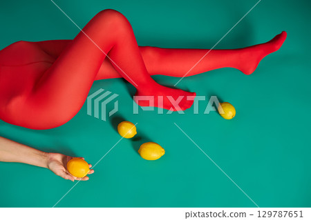 Woman with beautiful long legs in bright red tights relax lying on turquoise floor background Woman with beautiful long legs in bright red tights relax lying on turquoise floor background 129787651