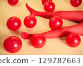 Long slim woman legs in red tights lying on beige background among red balloons 129787663
