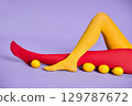 Long slim woman legs in multicolor yellow and red tights relax over purple studio background. 129787672