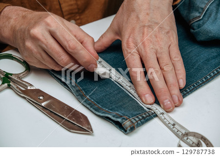 crafting custom jeans with chalk markings and precise measuring in small tailor shop. closeup. 129787738