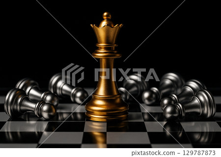 A golden king chess piece standing victorious among fallen black pieces representing ultimate leadership power and triumph A golden king chess piece standing victorious among fallen black pieces representing ultimate leadership power and triumph 129787873