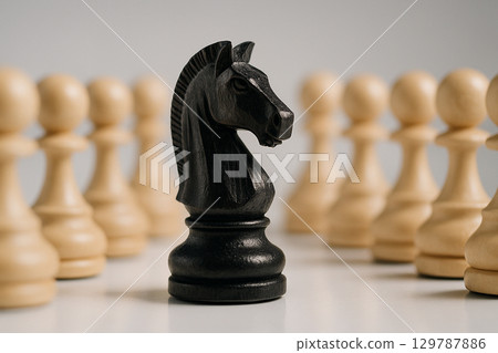 A black knight chess piece leads a row of pawns demonstrating unconventional strategy and leadership in challenging situations 129787886