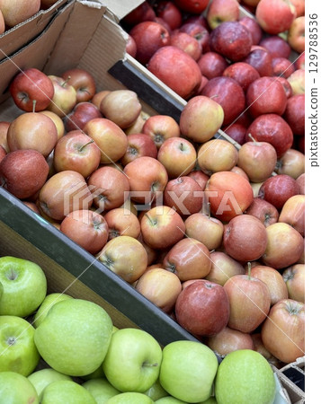 Box filled with fresh juicy natural bio organic red yellow apples placed on counter in local food market. Close-up 129788536