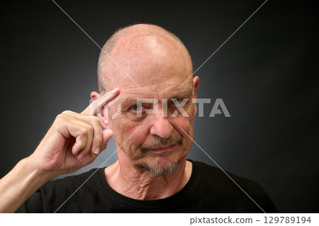 Closeup portrait of a elderly man in studio making a salut Closeup portrait of a elderly man in studio making a salut 129789194