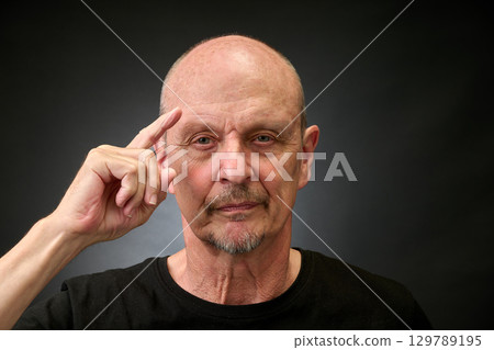 Closeup portrait of a elderly man in studio making a salut Closeup portrait of a elderly man in studio making a salut 129789195