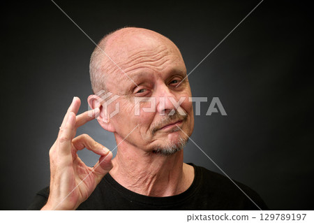 Closeup portrait of a elderly man in studio doying the sign for perfect Closeup portrait of a elderly man in studio doying the sign for perfect 129789197