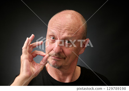 Closeup portrait of a elderly man in studio doying the sign for perfect 129789198