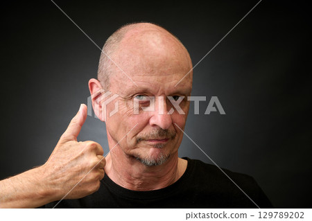 Closeup portrait of a elderly man in studio with thumbs up 129789202