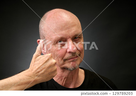 Closeup portrait of a elderly man in studio with thumbs up 129789203