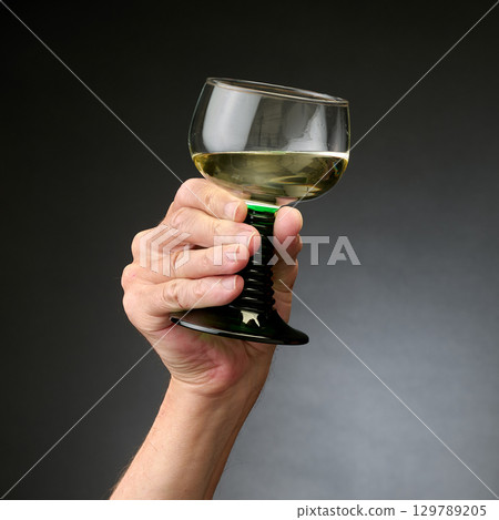 Glaass of white wine in a man s hand 129789205