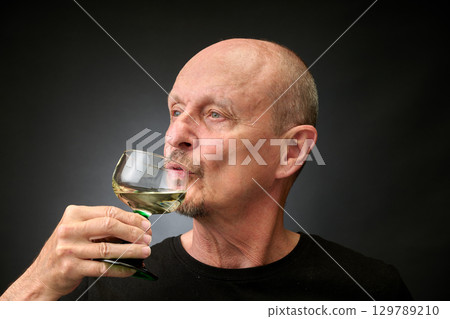 Closeup portrait of a senior man tasting a good white wine Closeup portrait of a senior man tasting a good white wine 129789210