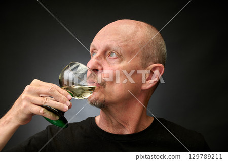 Closeup portrait of a senior man tasting a good white wine 129789211