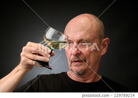 Closeup portrait of a senior man tasting a good white wine Closeup portrait of a senior man tasting a good white wine 129789214