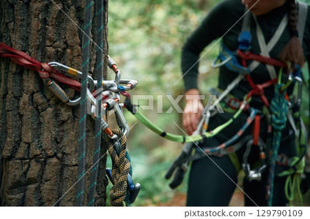 Close up particle view. Man is doing climbing in the forest by use of safety equipment Close up particle view. Man is doing climbing in the forest by use of safety equipment 129790109