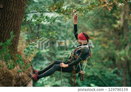 Woman is doing climbing in the forest by the use of safety equipment 129790139