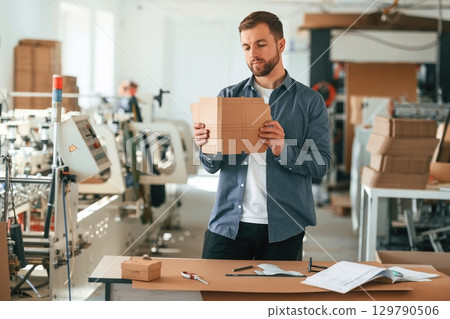Conception of labor. Handsome man is working at the factory of creating eco boxes Conception of labor. Handsome man is working at the factory of creating eco boxes 129790506
