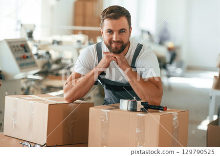 Bunch of eco boxes. Handsome man is working at the factory Bunch of eco boxes. Handsome man is working at the factory 129790525