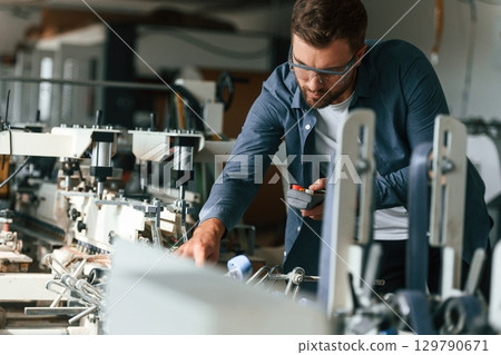 Working with machine. Handsome man is at the factory of creating eco boxes 129790671