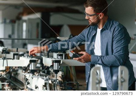 Working with machine. Handsome man is at the factory of creating eco boxes 129790673