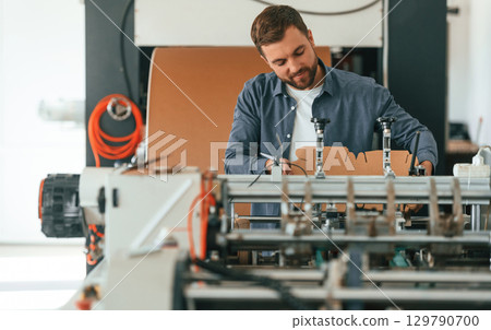 Front view. Handsome man is working at the factory of creating eco boxes 129790700
