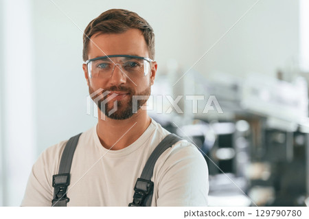 Close up portrait. Handsome man is working at the factory of creating eco boxes Close up portrait. Handsome man is working at the factory of creating eco boxes 129790780