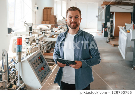 Single employee. Handsome man is working at the factory of creating eco boxes Single employee. Handsome man is working at the factory of creating eco boxes 129790796