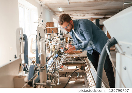 Single employee. Handsome man is working at the factory of creating eco boxes Single employee. Handsome man is working at the factory of creating eco boxes 129790797
