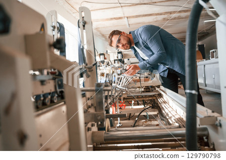 Single employee. Handsome man is working at the factory of creating eco boxes Single employee. Handsome man is working at the factory of creating eco boxes 129790798