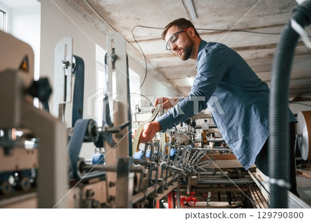Single employee. Handsome man is working at the factory of creating eco boxes Single employee. Handsome man is working at the factory of creating eco boxes 129790800