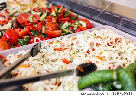 A close-up of fresh salads on a buffet counter, including a pickled cabbage slaw and a tomato salad. A close-up of fresh salads on a buffet counter, including a pickled cabbage slaw and a tomato salad. 129790811