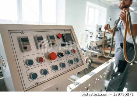 Standing by the machine. Handsome man is working at the factory of creating eco boxes 129790871