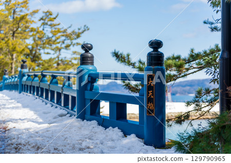 Amanohashidate in winter, snow-covered pine trees and the blue Daitenkyo Bridge 129790965