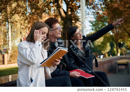 Sitting together. Three young students are outside the university outdoors 129791455