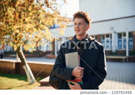 Young student is outside the university, in black clothes 129791498