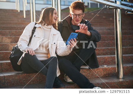 Having a break. Two young students are together outdoors Having a break. Two young students are together outdoors 129791515
