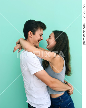 Young Couple Enjoying a Joyful Moment in Front of a Vibrant Teal Wall During a Sunny Day 129791722