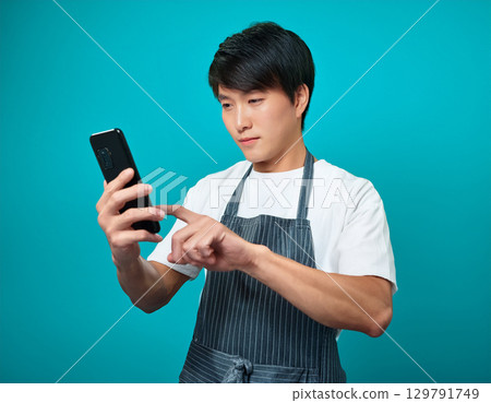 一名男子穿著圍裙尋找食譜 129791749