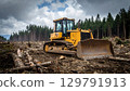 Yellow bulldozer is positioned in deforested area, surrounded by tree stumps and logs, under cloudy sky. scene conveys sense of industrial activity and environmental change 129791913