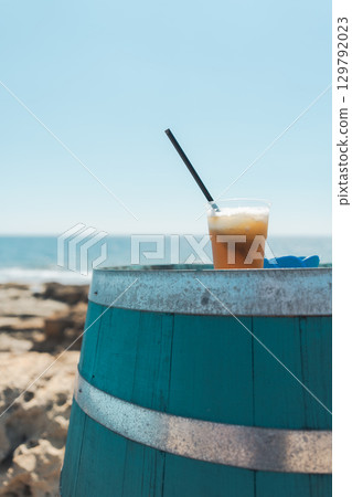 Iced drinks in blue barrels on the Italian seaside and blue summer sky 129792023