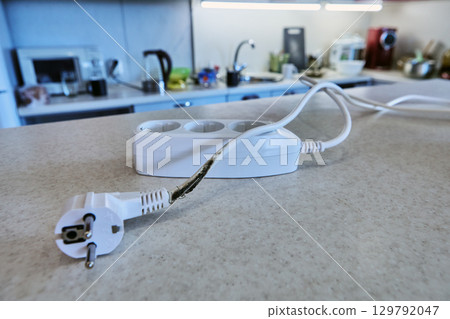An extension tee with charred power cord lies on table, unsuitable for further use. An extension tee with charred power cord lies on table, unsuitable for further use. 129792047