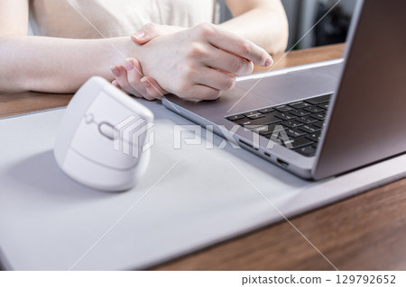 Person experiencing wrist pain from prolonged computer use, with an ergonomic vertical mouse on desk, highlighting carpal tunnel syndrome prevention Person experiencing wrist pain from prolonged computer use, with an ergonomic vertical mouse on desk, highlighting carpal tunnel syndrome prevention 129792652