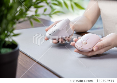 Person compares two computer mice, highlighting a comfortable white vertical ergonomic option and a compact pink wireless model, for efficient modern office work Person compares two computer mice, highlighting a comfortable white vertical ergonomic option and a compact pink wireless model, for efficient modern office work 129792655