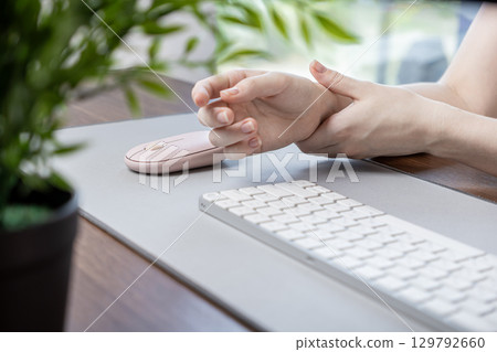 Person clutching painful wrist from extended computer mouse use, indicating a repetitive strain injury and ergonomic health concerns in modern digital workspace 129792660