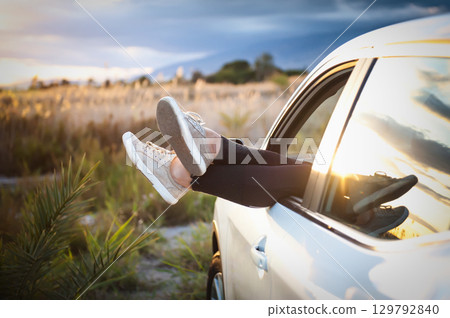 Women's legs out of car window Women's legs out of car window 129792840