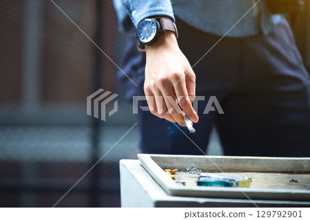 Man hand putting out cigarette on street ashtray, cigarette butt, smoking is dying. Quit smoking. Health concept. 129792901